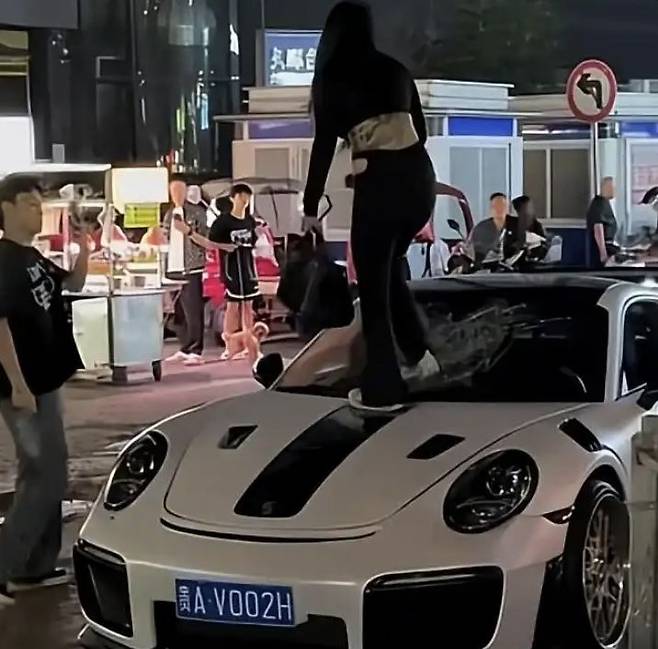 [뉴시스] 중국 구이양 시내에서 여성이 흰색 포르쉐 차량 위에 올라가 앞유리를 걷어차고 있는 장면.(사진=왕이신문)