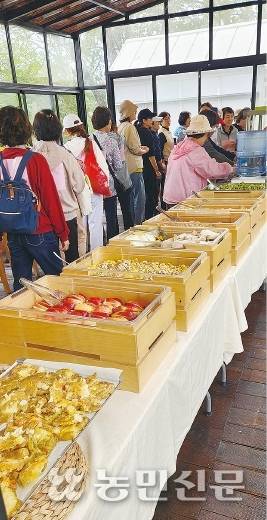 바비큐장에서 손님들이 지역 농특산물로 만들어 뷔페식으로 차린 음식을 접시에 담고 있다.