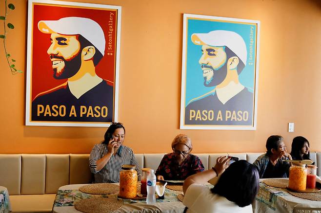 지난달 엘살바도르 수도 산살바도르의 한 카페에서 시민들이 휴식을 취하고 있다. 벽에는 '한 단계씩(paso a paso)'이라는 표현과 함께 나이브 부켈레 대통령의 그림이 보인다. /로이터 연합뉴스
