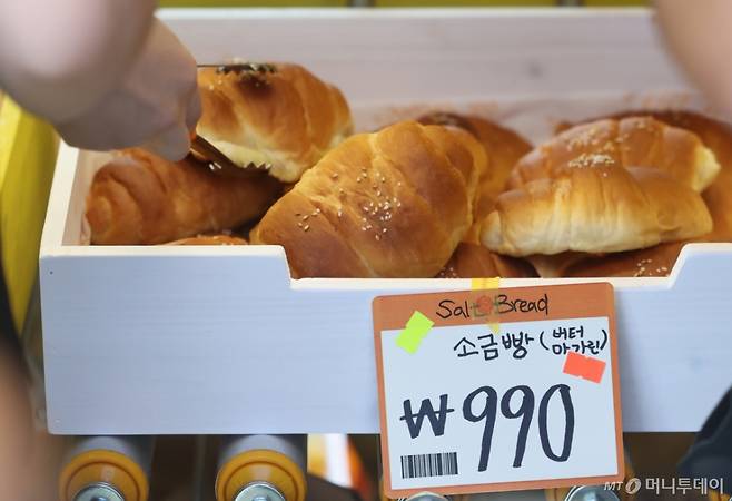 [서울=뉴시스] 황준선 기자 = 2일 오전 서울 성동구 글로우 성수에 마련된 유튜버 '슈카월드'의 베이커리 팝업 스토어 ETF베이커리를 찾은 시민들이 990원에 판매되는 소금빵을 고르고 있다.   슈카월드가 공간·브랜드 기획사인 글로우서울과 협업한 'ETF베이커리'는 빵과 인플레이션을 결합한 이른바 '빵플레이션' 프로젝트의 일환으로 지속적인 빵값 상승에 문제의식을 느끼고 시중보다 훨씬 낮은 가격으로 제품을 제공하는 것이 특징이다. 해당 팝업스토어에서는 소금빵 990원, 베이글 990원, 바게트 990원, 식빵 1990원, 명란바게트 2450원 등 전반적으로 파격적인 가격이 책정됐다. 2025.09.02. hwang@newsis.com /사진=황준선