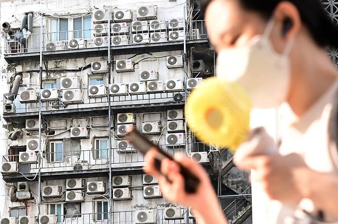 시민이 서울 중구 남대문 인근에 있는 건물 외벽에 줄지어 걸린 에어컨 실외기 앞을 지나가고 있다. 이상섭 기자