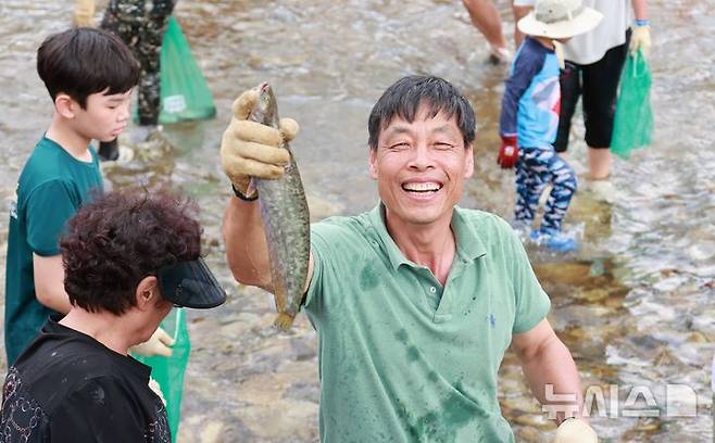 [괴산=뉴시스] 서주영 기자 = 6일 충북 괴산군의 동진천에서 열린 2025 괴산고추축제 프로그램 '고추물고기를 잡아라'의 한 참가자가 잡은 물고기를 들고 웃음을 짓고 있다. (사진= 괴산군 제공) 2025.09.06. photo@newsis.com