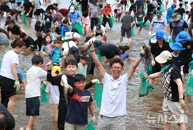 [괴산=뉴시스] 서주영 기자 = 6일 충북 괴산군의 동진천에서 열린 2025 괴산고추축제 프로그램 '고추물고기를 잡아라'의 한 참가자가 잡은 물고기를 들고 웃음을 짓고 있다. (사진= 괴산군 제공) 2025.09.06. photo@newsis.com