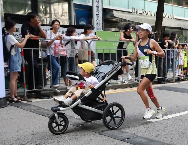 7일 서울 중구 서울광장에서 열린 ‘런 서울 런 2025(일간스포츠 서울마라톤)’에서 10km 여자부에 출전한 이윤경 씨가 아들 어준경 군이 탄 유모차를 밀며 피니시 라인을 통과하고 있다. 사진=일간스포츠 제공