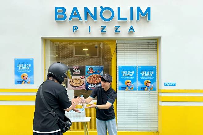 반올림피자 가맹 점주가 배달 라이더에게 생수를 전달하고 있다. /피자앤컴퍼니 제공