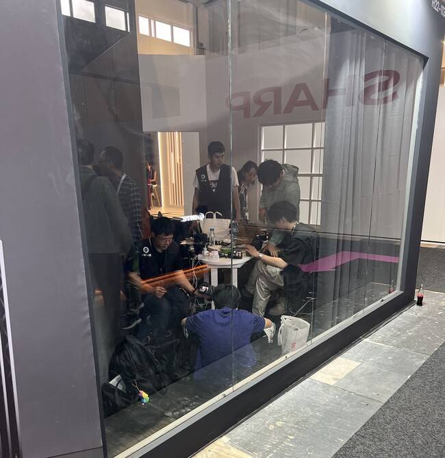 지난 5일(현지시각) 독일 베를린 국제 가전 전시회(IFA)의 레이저 프로젝터 분야 신생 기업인 ‘발레리온’ 전시관 뒤쪽에서 중국 청년들이 도시락을 먹으며 일하고 있다. 박종오 기자