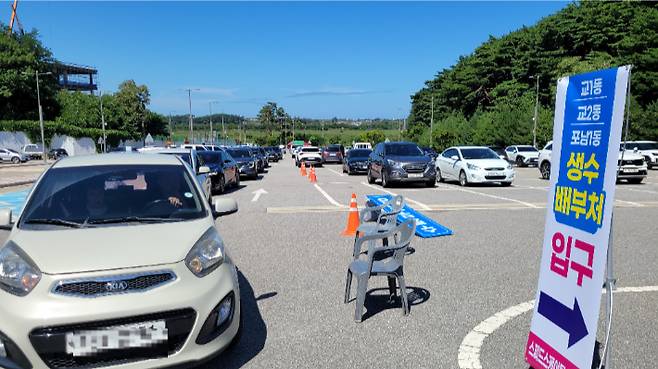 지난 5일 오후 강릉시 스피드스케이팅경기장 주차장에 마련한 '드라이브 스루'를 통해 생수를 받으러 온 차량들이 늘어선 모습. 전영래 기자