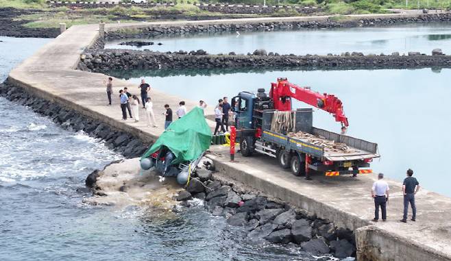 제주해경과 경찰 등 관계자들이 8일 오전 제주시 한경면 용수리 해안가에서 이날 오전 발견된 미확인 보트를 조사해 인양하려 하고 있다. 해경은 밀입국, 해양사고 등의 가능성을 열어 놓고 조사하고 있다고 밝혔다. (사진=연합뉴스)
