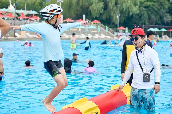 물 위에서 회전하는 원통 위에서 누가 더 오래 버티는지를 겨루는 한강수영장 이색스포츠 체험 ‘롤링 인 더 한강.’ [사진 서울시]