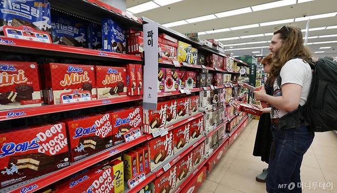 (서울=뉴스1) 박지혜 기자 = 지난달 라면·과자 등 K푸드의 대미(對美) 수출이 큰 폭으로 줄었다. 미국의 상호관세 불확실성으로 상반기에 수출이 앞당겨진 영향이라는 분석이다.  22일 한국농수산식품유통공사(KATI)에 따르면 7월 농수산식품 대미 수출액은 5437만 달러로 전년 동월 대비 1.6% 감소했다. 라면 수출액은 17.8% 줄었고, 과자류는 25.9% 감소하며 가장 큰 폭의 하락세를 보였다.  사진은 이날 서울의 한 대형마트 과자코너를 찾은 외국인 관광객 모습. 2025.8.22/뉴스1  Copyright (C) 뉴스1. All rights reserved. 무단 전재 및 재배포,  AI학습 이용 금지. /사진=(서울=뉴스1) 박지혜 기자