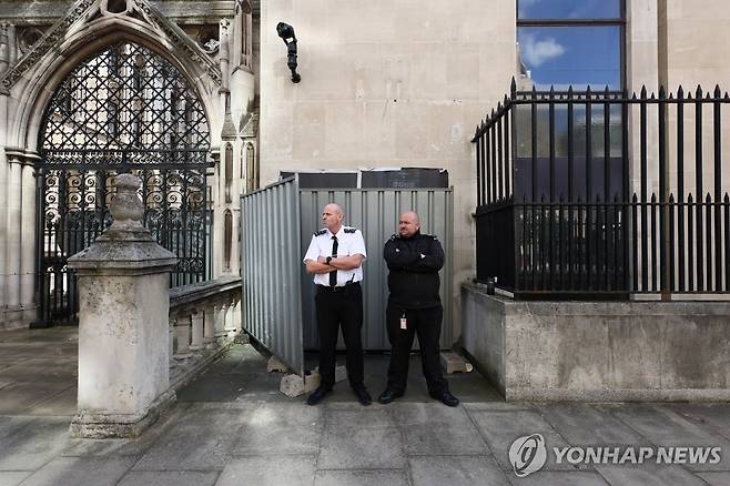 8일(현지시간) 영국 런던 왕립법원 외벽에 그려진 뱅크시의 벽화를 가린 차단막 앞에 보안 요원들이 서 있다.[로이터=연합뉴스. 재판매 및 DB 금지]