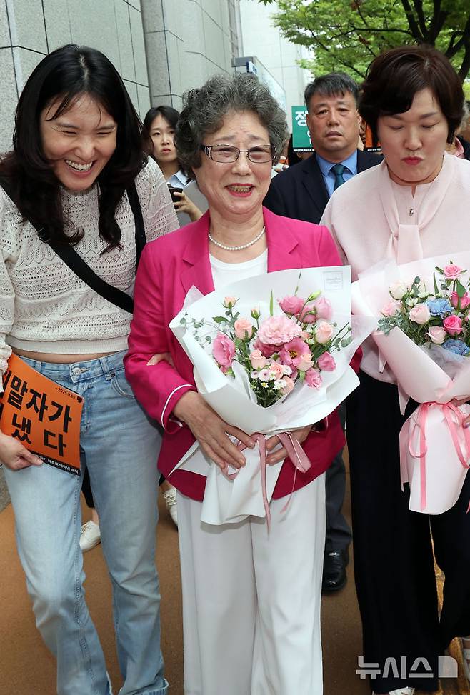 [부산=뉴시스] 하경민 기자 = 61년 전 성폭행에 저항하는 과정에서 가해자의 혀를 깨물어 1.5㎝가량 절단하는 상해를 입혔다는 이유로 가해자보다 더 중한 형을 선고받았던 최말자(79)씨가 재심에서 무죄를 선고받았다.  10일 부산 연제구 부산지방법원 앞에서 최씨가 여성단체 회원들과 함께 기자회견 장소로 이동하면서 환하게 웃고 있다. 2025.09.10. yulnetphoto@newsis.com
