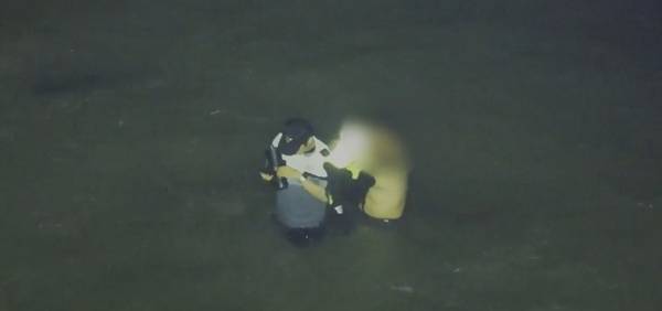 이 경사가 갯벌에 고립된 A씨에게 부력조끼를 벗어주고 있다. /인천해양경찰서 제공