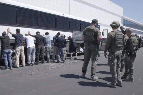This image from video provided by U.S. Immigration and Customs Enforcement via Dvids shows manufacturing plant employees waiting to have their legs shackled at a joint battery factory operated by Hyundai Motor Group and LG Energy Solution on Sept. 4 in Ellabell, Georgia. [AP/YONHAP]