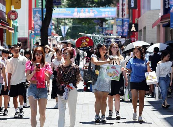 Visitors walk around Myeongdong, a shopping district in central Seoul, on July 27. [YONHAP]