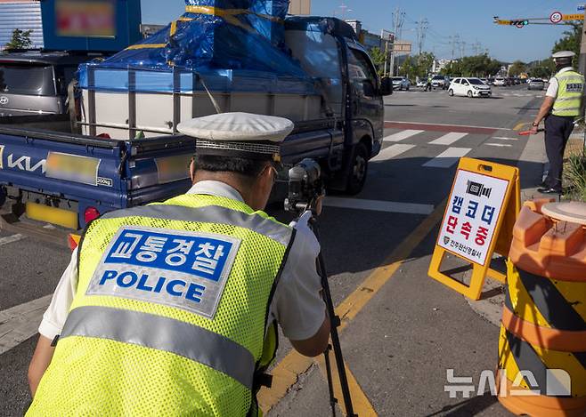 [전주=뉴시스] 강경호 기자 = 11일 오전 전북 전주시 완산구 효자동의 한 사거리에서 진행된 경찰의 '5대 반칙운전' 집중 단속 현장에서 경찰이 캠코더를 통해 교통법규 위반 여부를 촬영하고 있다. 2025.09.11. lukekang@newsis.com