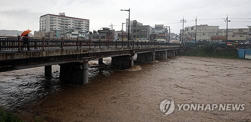 지난 7일 밤사이 내린 많은 비로 홍수주의보가 내려진 전북 전주시 전주천 서천교 인근 매곡교를 시민들이 건너고 있다. 연합뉴스 제공