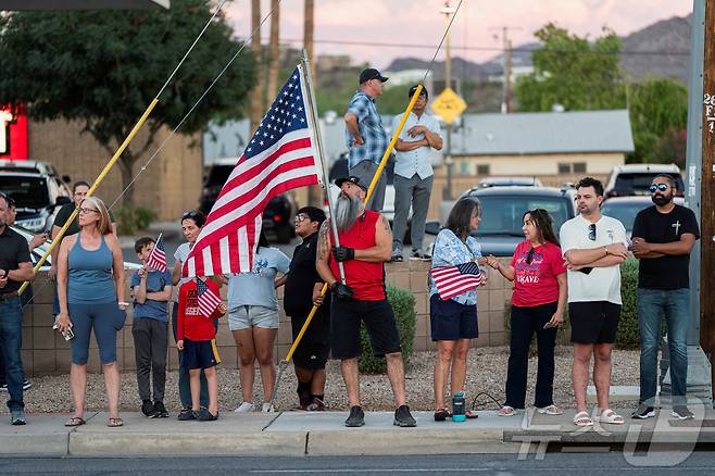 11일(현지시간) 총격으로 피살된 미국의 극우성향 논객 찰리 커크의 시신이 안치된 애리조나주 피닉스의 장례식장에 그의 지지자들이 성조기를 들고 모여 있다. 2025.09.11 ⓒ 로이터=뉴스1 ⓒ News1 김지완 기자
