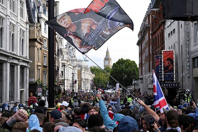 영국 수도 런던에서 13일(현지시간) 극우 단체가 개최한 반이민 시위 현장에 도널드 트럼프 미국 대통령을 ‘람보’로 묘사한 깃발이 휘날리고 있다. 로이터연합뉴스