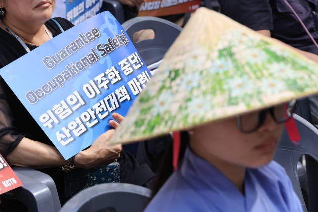 지난달 24일 서울지방노동청 앞에서 이주노동자 평등연대·대한불교조계종 사회노동위원회 주최로 열린 2025년 온열·산재·괴롭힘 사망 이주노동자 추모와 베트남 청년노동자 응오뚜이롱 49재에서 한 참석자가 피켓을 들고 있다. 연합뉴스