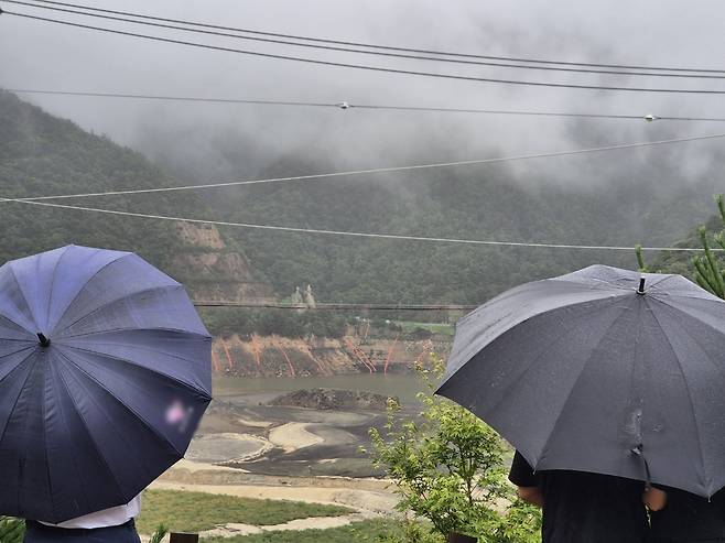 극심한 가뭄을 겪고 있는 강원 강릉지역에 비가 내린 13일 오전 우산을 쓴 시민이 마른 저수지에 내리는 단비를 바라보고 있다. 2025.9.13 뉴스1