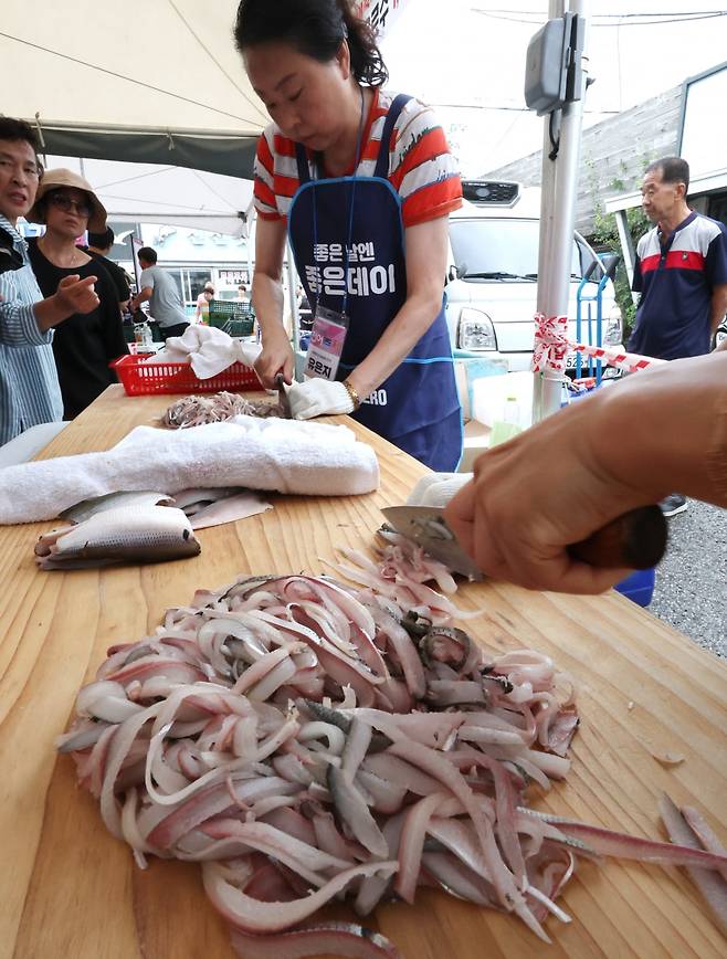 지난 9일 부산 강서구 명지시장 일원에서 열린 제23회 명지시장 전어축제에서 '상인솜씨 경연대회'에 참가한 상인들이 싱싱한 전어를 썰고 있다. 연합뉴스