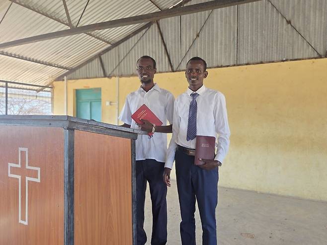 소라 아미요와 쿠레와 심데니아가 케냐 코어에 위치한 말리왁교회 강대상 옆에 서 있는 모습.