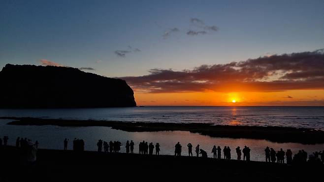 2025년 을사년(乙巳年) 첫날인 1월 1일 제주 서귀포시 성산일출봉 인근 해변에서 사람들이 일출을 보며 새해 소망을 빌고 있다. 뉴스1