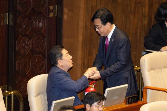 국민의힘 송언석(오른쪽), 더불어민주당 김병기 원내대표가 16일 국회 본회의에서 손을 맞잡고 대화하고 있다. 뉴스1