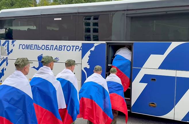 지난달 24일 벨라루스에서 진행된 러시아와 우크라이나 간 포로 교환에서 풀려난 러시아 군인들이 러시아 국기를 두른 채 버스에 탑승하는 모습. 러시아 국방부가 공개한 영상의 일부로 사진은 기사와 직접적 관련은 없음. /EPA 연합뉴스