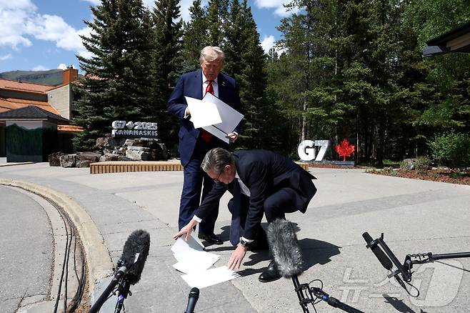 키어 스타머 영국 총리가 2025년 6월 16일 캐나다 앨버타주 캐내내스키스에서 열린 주요 7개국(G7) 정상회의 도중, 도널드 트럼프 미국 대통령이 기자들과 이야기하는 동안 떨어뜨린 서류를 주워주고 있다. 2025.6.16 ⓒ 로이터=뉴스1 ⓒ News1 강민경 기자