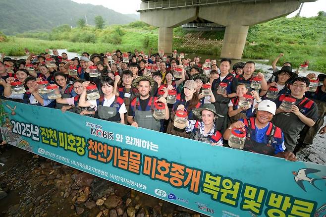 현대모비스 국내외 임직원이 지난 17일 충북 진천군 미호강 일대에서 멸종위기종인 미호종개 치어 방류 행사에서 기념촬영을 하고 있다. 현대모비스 제공