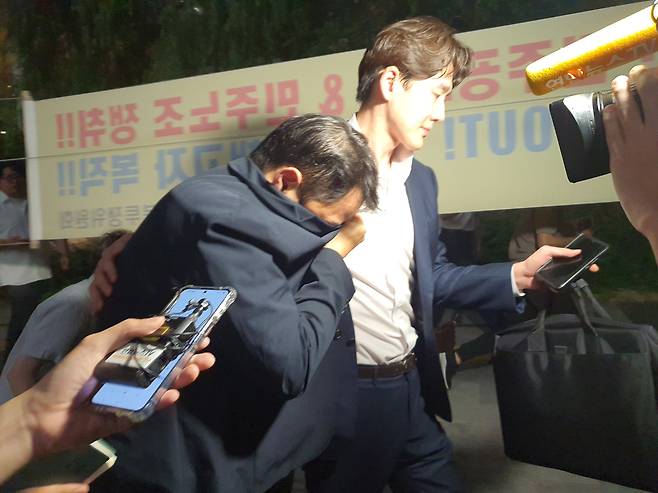 김건희 여사의 오빠 김진우씨가 지난 7월 28일 오후 김건희 특검팀 조사를 마치고 옷깃으로 얼굴을 가린 채 변호인 부축을 받으며 취재진을 피해 걸어가고 있다. /뉴스1