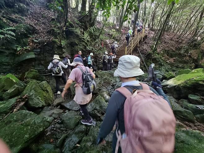 제주 한라산둘레길 오감걷기에 참여한 산하클럽 회원들이 계곡을 건너고 있다.