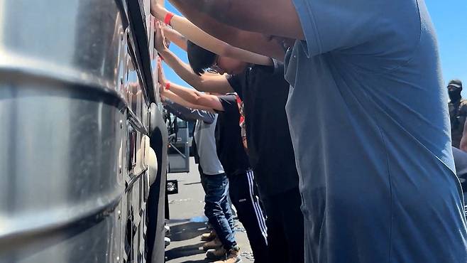 Detainees are made to stand against a bus before being handcuffed, during a raid by federal agents where about 300 Koreans were among 475 people arrested at the site of a $4.3 billion project by Hyundai Motor and LG Energy Solution to build batteries for electric cars in Savannah, Georgia on Sept. 4. [REUTERS/YONHAP]