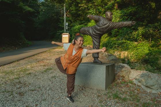 A foreign visitor mimics the pose of a sunmudo statue for a commemorative photo at Golgul Temple on Aug. 21. [BAEK JONG-HYUN]