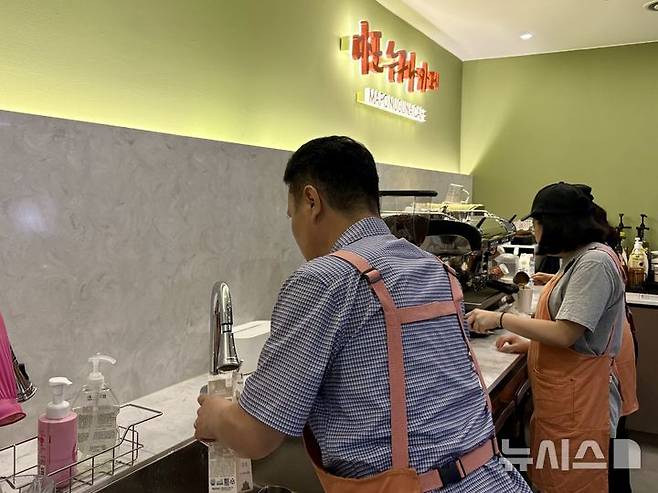 [서울=뉴시스] 한이재 기자 = 17일 오전 서울 마포구에 있는 누구나 카페에서 김모(58)씨가 다 쓴 우유팩을 분리 배출하기 위해 씻고 있다. 2025.09.18. nowone@newsis.com