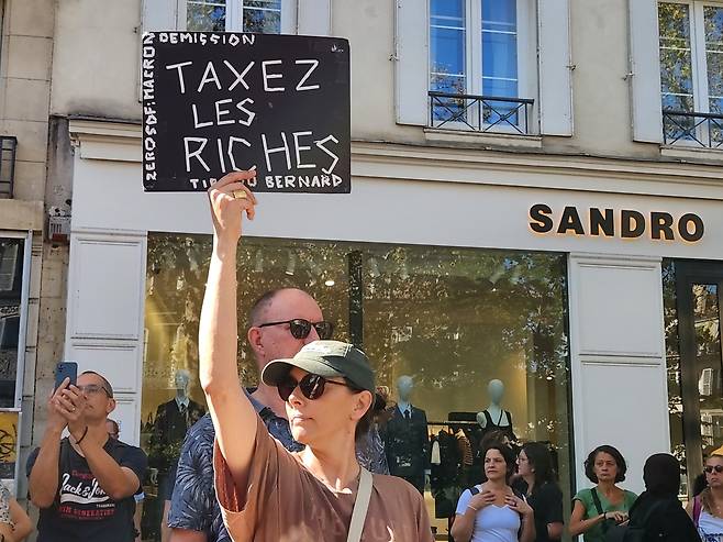 '부자에 세금을' (파리=연합뉴스) 송진원 특파원 = 18일(현지시간) 프랑스 파리 바스티유 광장에서 시작된 행진에 참여한 한 시민이 '부자에게 과세하라'는 손팻말을 들고 있다. san@yna.co.kr. 2025.09.18.