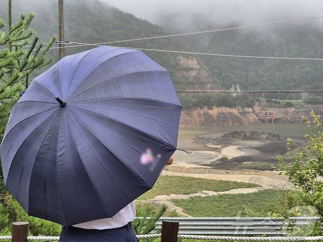 극심한 가뭄을 겪고 있는 강원 강릉지역에 많은 비가 내린 지난 13일 오전 우산을 쓴 시민이 마른 저수지에 내리는 단비를 바라보고 있다. 2025.9.13/뉴스1 ⓒ News1 윤왕근 기자