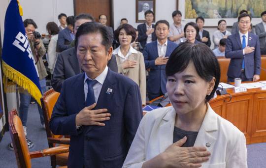 민주당 정청래 대표와 김병기 원내대표를 비롯한 당 관계자들이 18일 국회에서 열린 서울·인천·강원 예산정책협의회에 참석해 국기에 경례하고 있다. 연합뉴스