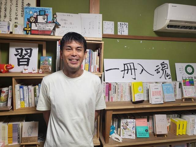 미시마 구니히로 미시마사 대표가 출판사의 철학 ‘일책입혼’이 쓰여진 팻말 앞에서 환하게 웃고 있다.