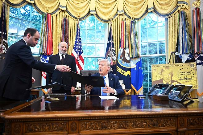 도널드 트럼프 미국 대통령이 19일(현지시간) 백악관에서 행정명령 문서를 건네받고 있다. [AFP]