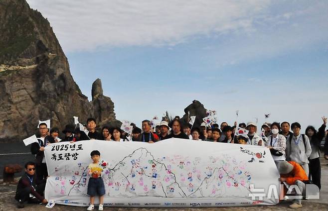 [서울=뉴시스] '2025 독도탐방' 참가자들이 손도장이 찍힌 초대형 독도기를 펼치고 기념사진을 찍고 있는 모습.