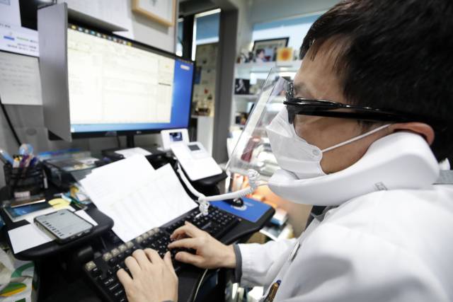 2022년 2월 서울의 한 이비인후과 원장이 코로나19 확진판정을 받은 환자와 전화로 비대면 진료를 하고 있다. 연합뉴스