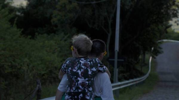 다큐멘터리 영화 ‘나나와의 왕자’ 스틸. 어린 앙헬이 제작진이자 어른에게 업혀 길을 건너고 있다. DMZ국제다큐멘터리영화제 제공