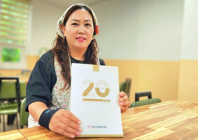 ▲ 전수경 사무국장이 20주년 기념 백서 '함께해온 20년, 함께 할 20년'을 들고 환하게 웃고 있다.