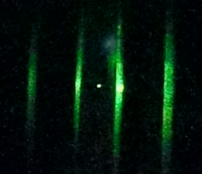 137나노미터 크기의 유리 입자(가운데 하얀 점)가 초록색으로 보이는 레이저 빔 사이에 떠 있다. Kamba et al.(2025)/Science 제공