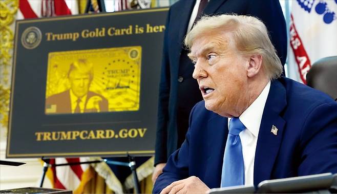 도널드 트럼프 미국 대통령이 지난 19일 ﻿전문직(H-1B) 비자 발급 수수료를 10만달러로 인상하고 100만달러를 내면 영주권을 받을 수 있는 ‘골드카드’ 신설 행정명령에 서명한 뒤 취재진 질문에 답하고 있다. 트럼프 대통령 옆에 골드카드 견본 이미지가 전시돼 있다. 사진=AP연합뉴스
