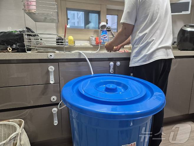 강원 강릉지역 저수조 용량 100톤 이상 아파트 113곳에 대한 시간제 제한급수가 풀린 지난 19일 저녁 강릉 회산동의 한 아파트 주민이 수돗물을 이용해 설거지를 하고 있다. 싱크대 근처에 그동안 받아놓은 물을 아끼려고 달아놓은 샤워헤더와 물통이 놓여 있다.2025.9.19/뉴스1 ⓒ News1 윤왕근 기자