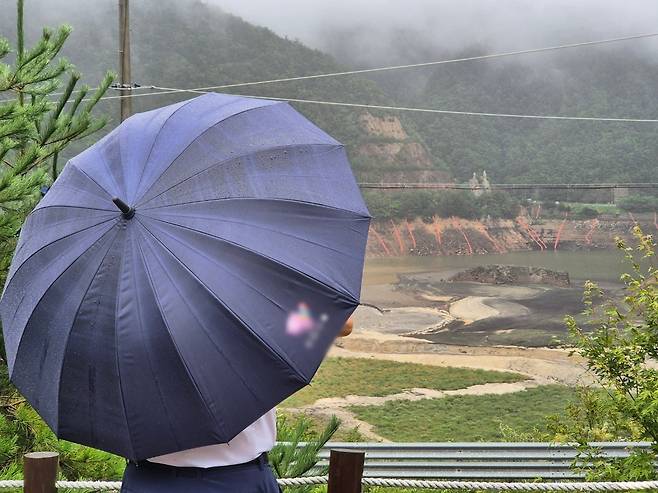 극심한 가뭄을 겪고 있는 강원 강릉지역에 많은 비가 내린 지난13일 오전 우산을 쓴 시민이 마른 저수지에 내리는 단비를 바라보고 있다./뉴스1